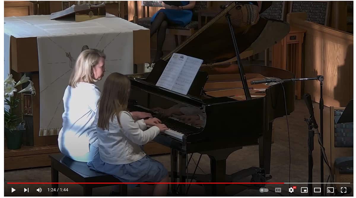 woman and girl playing the piano at a recital